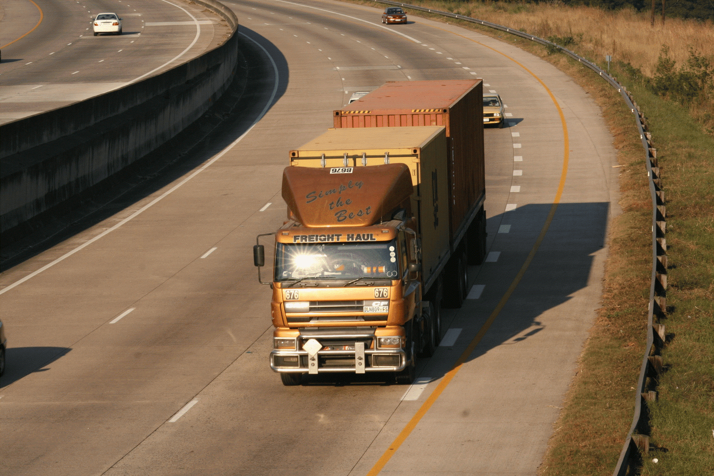 An articulated lorry hauling a shipping container along a multi-lane highway